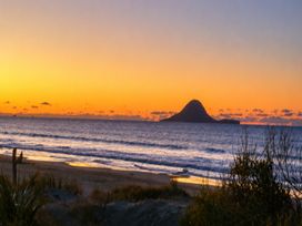A beach view at sunset with ocean and island at Coastal Haven Retreat - 4 Bedrooms Ohope Beach