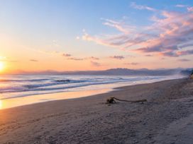 A beach with sand and ocean at Coastal Haven Retreat - 4 Bedrooms Ohope Beach