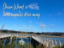 A pier with a boat in water at Ohiwa Wharf near Ohope Beach