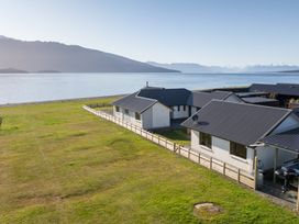 An outdoor area with houses near a lake at The Tranquil Edge - Te Anau Holiday Home in Te Anau