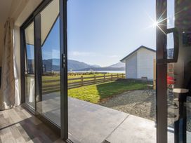 A view from a sliding door showing a grassy area and mountains at The Tranquil Edge - Te Anau Holiday Home