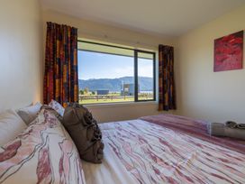 A bedroom with a bed and window view at The Tranquil Edge - Te Anau Holiday Home Te Anau