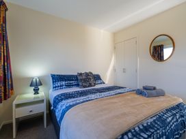 A bedroom with a bed and nightstand at The Tranquil Edge - Te Anau Holiday Home
