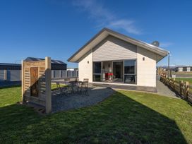 A house with a table and chairs in the yard at The Tranquil Edge - Te Anau Holiday Home in Te Anau