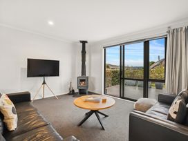 A living room with a television and wood stove at Vista Haven - Bannockburn