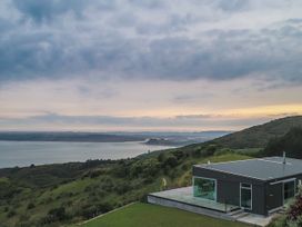 A house with a deck overlooking the ocean at The Glass House - Raglan Escape in Raglan
