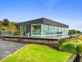 A house with glass walls and a deck at The Glasshouse at Block295 Raglan