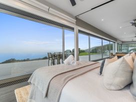 A bedroom with a bed facing large windows at The Glasshouse at Block295 Raglan