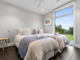 A bedroom with two beds and a window overlooking the garden at The Glasshouse at Block295 Raglan