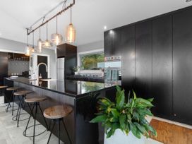 A kitchen with an island and bar stools at The Glasshouse at Block295 Raglan