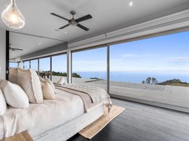 A bedroom with a bed and large windows overlooking the outdoor view at The Glasshouse at Block295 Raglan