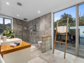 A bathroom with a sink, toilet, shower, and window at The Glasshouse at Block295 Raglan