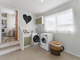 A laundry room with washing machine, dryer, and sink at The Flax Cottage - National Park