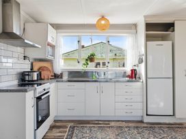 A kitchen with appliances and cabinets at The Flax Cottage - National Park Holiday Home