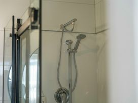 A shower setup with a glass panel in The Flax Cottage - National Park