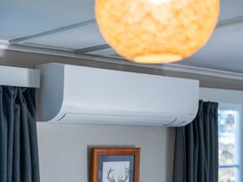 A living room with an air conditioner and a framed picture at The Flax Cottage - National Park Holiday Home