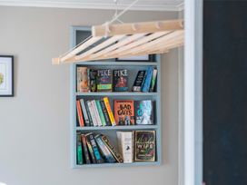 A bookshelf filled with books and a clothes drying rack at The Flax Cottage - National Park