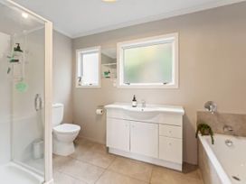 A bathroom with a shower, toilet, sink, and vanity at Acacia Horizons - Taupo Holiday Home, Acacia Bay