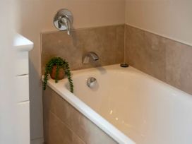 A bathtub with a faucet and a plant at Acacia Horizons - Taupo Holiday Home, Acacia Bay