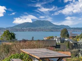 A view of a lake and mountain from a patio at Acacia Horizons - Taupo Holiday Home Acacia Bay
