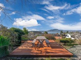 A deck with a table and chairs overlooking water at Acacia Horizons - Taupo Holiday Home in Acacia Bay