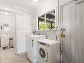 A laundry room with a washing machine, dryer, and sink at Rotorua Holiday Home in Rotorua