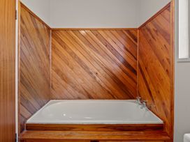 A bathtub with wood paneling in a bathroom at Rotorua Holiday Home in Rotorua