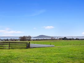 A scenic view of a grassy area with a fence and a lake at Rotorua located in Rotorua