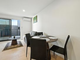 A living room with a sofa and dining table at Central Crossing - Christchurch Holiday Home in Christchurch