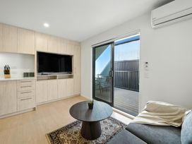 A living room with a sofa, coffee table, and television at Central Crossing - Christchurch Holiday Home