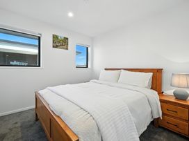 A bedroom with a bed and windows at Central Crossing - Christchurch Holiday Home in Christchurch