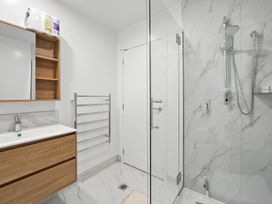 A bathroom featuring a sink, mirror, towel rail, and glass shower at Central Crossing - Christchurch Holiday Home, Christchurch