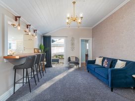 A living room with a sofa and bar stools at Creed Cottage - Whitianga Holiday Home