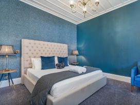 A bedroom with a bed, side tables, lamps, and an armchair at Creed Cottage - Whitianga