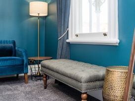 A sitting room with an armchair, table, bench and lamp at Creed Cottage - Whitianga Holiday Home Whitianga
