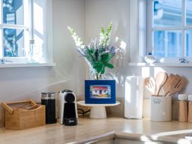 A kitchen countertop with a coffee machine and flower arrangement at Creed Cottage - Whitianga Holiday Home in Whitianga