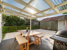 An outdoor patio with a table and bench at Creed Cottage - Whitianga