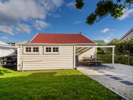 A house with a red roof and outdoor seating area at Creed Cottage - Whitianga Holiday Home in Whitianga