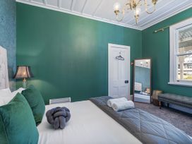 A bedroom with a bed and a mirror at Creed Cottage - Whitianga Holiday Home in Whitianga