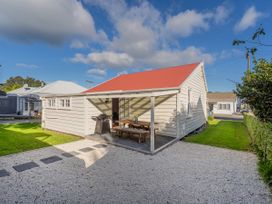 A house with a red roof and outdoor seating at Creed Cottage - Whitianga Holiday Home in Whitianga