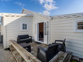 An outdoor area with seating and a door leading into the house at Creed Cottage - Whitianga