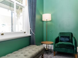 A sitting room with a window, lamp, chair, side table, and ottoman at Creed Cottage - Whitianga Holiday Home Whitianga
