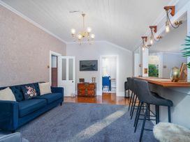 A living room with a sofa and chandelier at Creed Cottage - Whitianga Holiday Home Whitianga