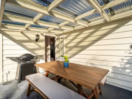 An outdoor patio with a table, benches, and a grill at Creed Cottage - Whitianga