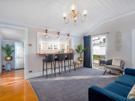 A living room with a bar counter and chairs at Creed Cottage - Whitianga