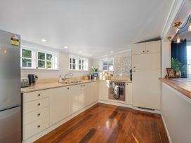 A kitchen with a refrigerator, sink, stove, and cabinets at Creed Cottage - Whitianga