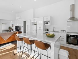A kitchen with an island and bar stools at Arbor Villa - Greytown Holiday Home Greytown