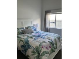A bedroom with a bed covered in a floral bedspread at Arbor Villa - Greytown Holiday Home Greytown