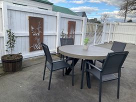 A patio area with a round table and chairs at Arbor Villa - Greytown Holiday Home, Greytown