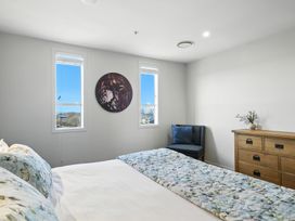 A bedroom with a bed, chair, and dresser at Downtown Haven - Christchurch Holiday Apartment in Christchurch